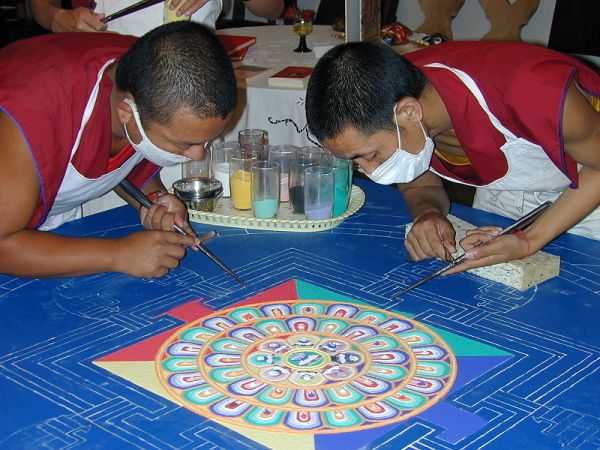 Tibetian monks creating elaborate colored sand mandala.